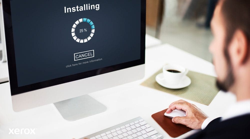 Xerox® Smart Start: Simple and Quick Installation A close-up view of a computer monitor displaying an "Installing" progress bar at 25%, with a person's hand on a computer mouse next to a coffee cup, illustrating easy software setup.